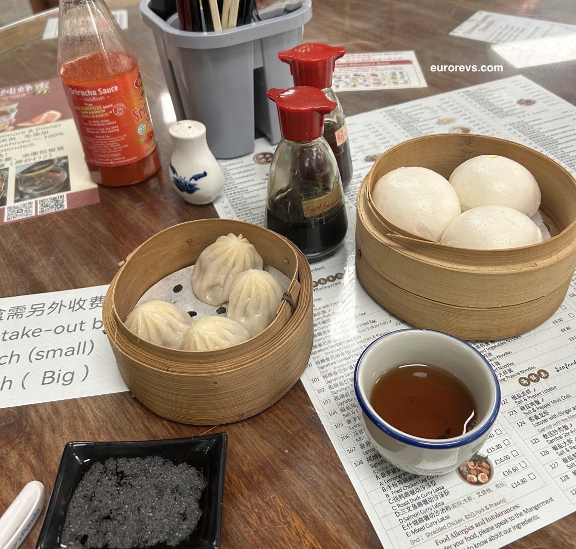 xiao long bao in a bamboo basket alongside Chinese steamed custard buns  